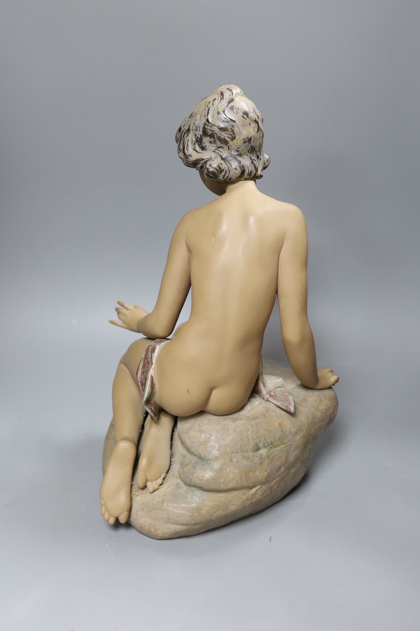 A large Lladro stoneware figure of a young girl seated on a rock, 42cm